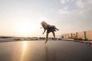 menina pular e se divertir no trampolim no verão foto