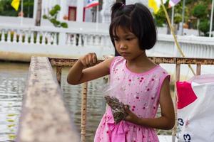 a menina da Tailândia está alimentando os peixes foto