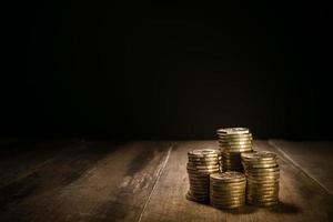 pilhas de moedas de ouro em um fundo escuro natural foto