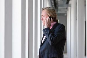 homem de negócios, ligando com o celular no escritório branco. foto