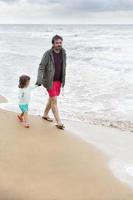 foto autêntica sobre pai e filha caminhando na praia