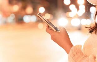 imagem de close-up da mão feminina usando smartphone móvel na rua da cidade à noite. conceito de pesquisa ou redes sociais. foto