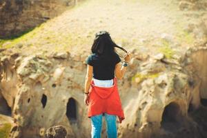 pessoa do sexo feminino fica olhe sobre fundo dramático vale com casas de caverna. exploração solo na Turquia. destino de viagem cinematográfica 2022.
