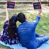 casal indiano posando para ensaio de maternidade. o casal está posando em um gramado com grama verde e a mulher está vacilando sua barriga no jardim lodhi em nova delhi, índia foto