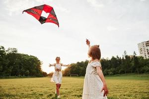 quero te abraçar. mãe e filha se divertem com pipa no campo. natureza bela foto