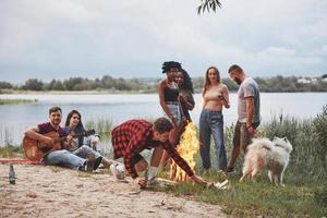 bom reencontrar. grupo de pessoas faz piquenique na praia. amigos se divertem no fim de semana foto