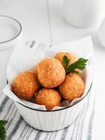 delicioso bitterballen caseiro feito de farinha, queijo, leite coberto com miolo de pão recheado com mussarela. servido em tigela branca. imagem de foco seletivo. foto