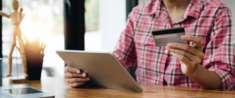 close-up de garota negra segurar o cartão de crédito do banco e digitar no  laptop