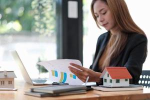 agente de mulher de negócios calculando empréstimo de finanças e investimento para imóveis, mulher de negócios e investe em propriedade sobre casa, construção ou hipoteca de casa. foto