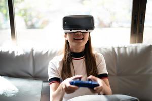 conceito de tecnologia, jogos, entretenimento e pessoas. mulher asiática desfrutando de óculos de realidade virtual enquanto relaxa na sala de estar. cara jovem feliz com fone de ouvido vr jogando videogame em casa foto