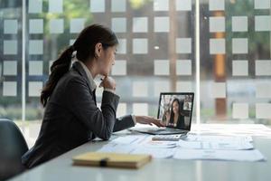 mulher de negócios conversando com seus colegas sobre o plano em videoconferência. equipe de negócios multiétnica usando laptop para uma reunião online em videochamada. grupo de pessoas inteligentes trabalhando em casa foto