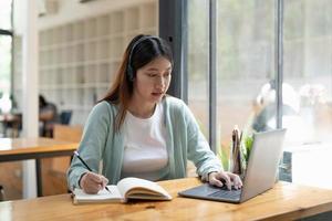 foto recortada de mulher escrevendo fazendo lista tomando notas no bloco de notas trabalhando ou aprendendo no laptop dentro de casa - curso educacional ou treinamento, seminário, conceito on-line de educação