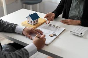 corretor de imóveis segurando a chave da casa para seu cliente após a assinatura do contrato, conceito de imóveis, mudança de casa ou aluguel de propriedade foto
