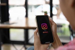mulher segurando iphone 13 pro max com aplicativo instagram na tela. instagram é um serviço de rede social online popular foto