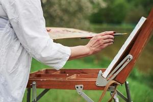 visão de partículas do pintor feminino adulto trabalhando na pintura ao ar livre foto