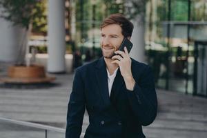 empresário de homem confiante vestido com roupas formais faz telefonema em roaming foto