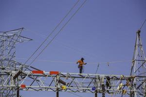 macho andando na viga instalação de postes de eletricidade de transmissão de alta tensão foto