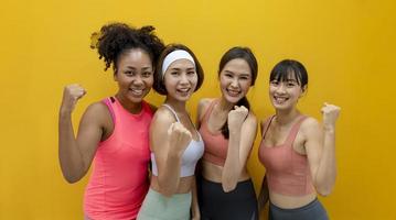 retrato de grupo de mulheres atletas de diversidade saudável e magra em roupas esportivas sorrindo no fundo amarelo isolado para o conceito de exercício e treino foto