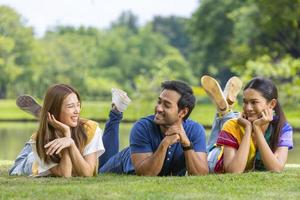 grupo de amigo estudante universitário está relaxando deitado na grama no campus universitário perto do lago para recreação e conceito de estilo de vida de felicidade foto