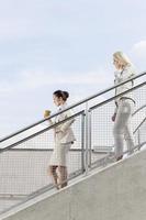 foto de perfil de mulheres de negócios descendo as escadas juntos contra o céu