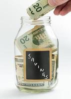 mão inserir dinheiro em salvar jar ou banco foto