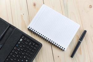 mesa de escritório com caderno, caneta e smartphone
