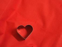 moldes de pão coração inoxidável em forma de tecido vermelho fundo, amor dia dos namorados para copiar cartão de texto, plano de fundo foto