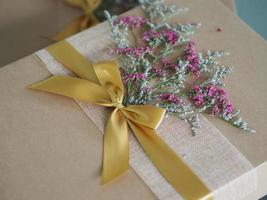 caixa de presente de papel pardo amarrada com uma fita dourada e decorada com flores secas, presentes do festival para o natal e feliz ano novo foto
