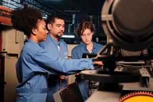 equipes de engenheiros profissionais multirraciais da indústria em uniformes de segurança trabalham inspecionando a corrente de tensão das máquinas, verificando e mantendo na fábrica de fabricação, ocupações de serviço do sistema elétrico. foto