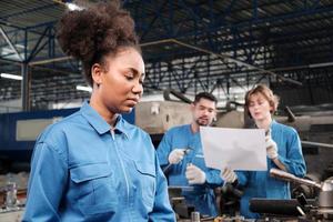 uma trabalhadora profissional engenheira da indústria afro-americana trabalha em uniforme de segurança com ferramentas de precisão de metalurgia, máquinas de torno mecânico e oficina de peças de reposição em uma fábrica de fabricação.
