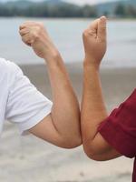 duas mulheres apertos de mão alternativos saudação de colisão de cotovelo na situação de uma epidemia covid 19, coronavírus novo distanciamento social normal, figura vertical foto