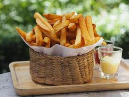 batatas fritas, batatas fritas amarelas crocantes na cesta de madeira, lanche de comida delicioso foto