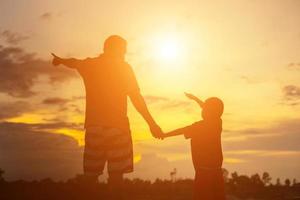 pai feliz joga o bebê ao pôr do sol foto