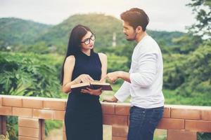 prática de educação jovem juntos digitando no laptop e lendo o livro. foto