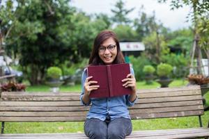 uma mulher sentada no jardim lendo um livro. foto