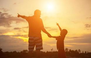 pai feliz joga o bebê ao pôr do sol foto