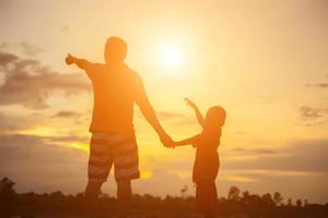 pai feliz joga o bebê ao pôr do sol foto