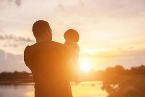 pai levou o bebê aprender a andar ao pôr do sol. foto