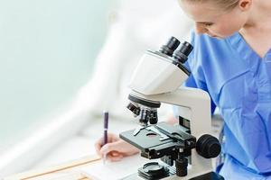 jovem estudante de doutorado adolescente na universidade médica trabalhando estudo vacina contra vírus no laboratório escolar com microscópio. foto