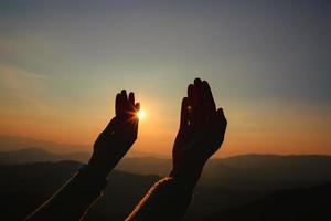 adoração de mãos de mulher no pôr do sol foto