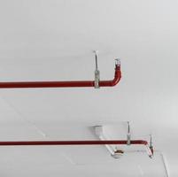 sprinkler de fogo e tubo vermelho no fundo do teto branco foto