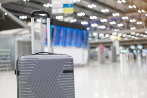 mala de bagagem no terminal do aeroporto internacional, mala de carrinho com placa de informações no fundo do aeródromo. conceitos de transporte, seguro, viagens e férias foto