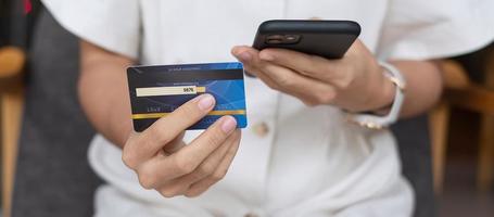 empresária segurando cartão de crédito e usando smartphone touchscreen para compras on-line enquanto faz pedidos no café ou escritório. negócios, tecnologia, comércio eletrônico e conceito de pagamento on-line