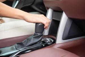 mulher motorista stick shift transmissão uma engrenagem do carro, volante controlando a mão durante o movimento do veículo. conceitos de transporte de viagem, viagem e segurança foto