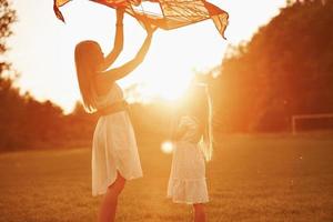 vai voar. mãe e filha se divertem com pipa no campo. natureza bela foto