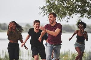 me pegue se for capaz. as pessoas fazem festa lá fora. amigos multiétnicos têm reunião no fim de semana foto