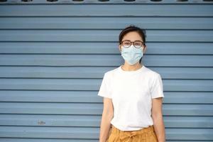 mulher usando máscara facial médica durante a caminhada na rua e no mercado noturno, previne o coronavírus ou a doença do vírus corona. saúde, conceito de vida foto