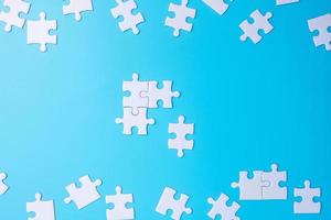 grupo de peças de quebra-cabeça branco sobre fundo azul. conceito de soluções, missão, sucesso, objetivos, cooperação, parceria, estratégia e dia de quebra-cabeça foto