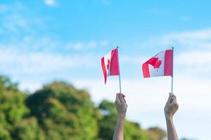 mão segurando a bandeira do Canadá no fundo do céu azul. dia do canadá e conceitos de celebração feliz foto