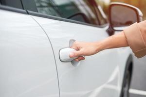 mão segurando a alça do carro inteligente e abrindo uma porta. conceito de transporte, viagens, serviços e aluguel de carros foto